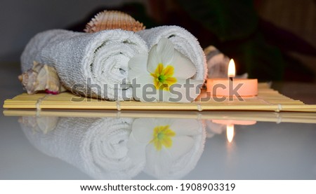 Thai massage spa objects, accessory on textile background, wellness and relaxation concept. Aromatherapy body care. Towel, burning candles, tropical flowers reflected on the table.