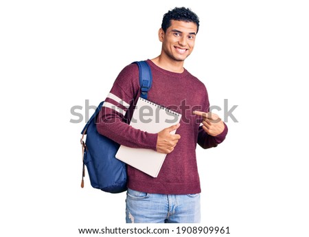 Hispanic handsome young man wearing student backpack and notebook smiling happy pointing with hand and finger  Royalty-Free Stock Photo #1908909961