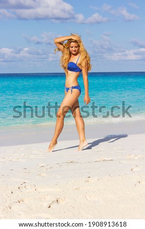 Blond woman walks along the beach.