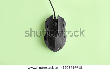 The matte modern black gaming mouse on a light green background.