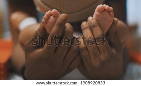 Black father playing with baby feet. Close up. High quality photo