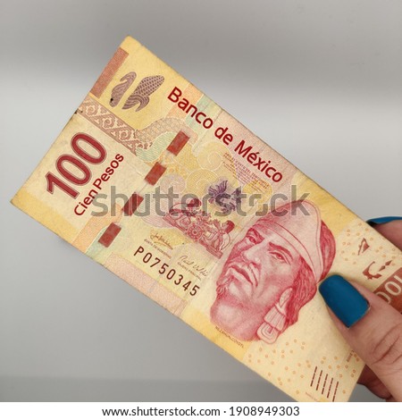 woman's hand holding a hundred Mexican peso bill money cash in hand