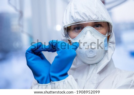Woman with a medical mask and hands in latex glove shows the symbol of the heart