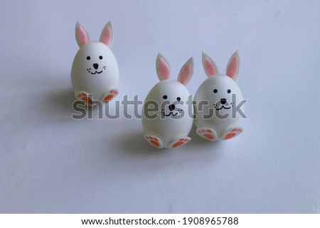 Three handmade bunnies are made of a chicken egg. Cardboard ears and paws. Easter holiday concept.