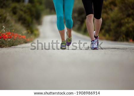 Detail photo of two woman running on a street in the landscape focus on their feet