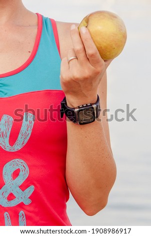 Detail photo of a sporty woman holding an apple during her training - healthy lifestyle