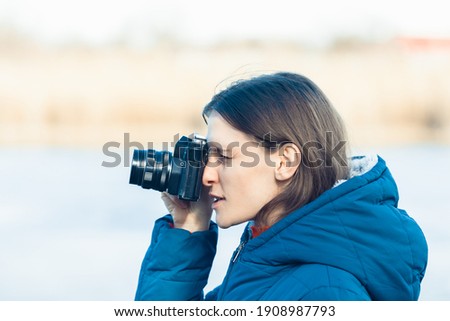 A tourist photographer takes pictures with a vintage retro film camera - a woman takes pictures at a photography lesson.