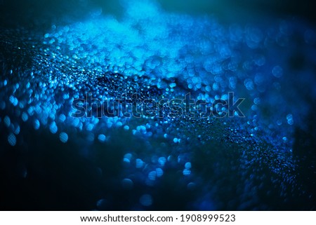 Blue glitter texture. Sequins scattered on a black background. Shimmering effect. Bokeh. Blurred background