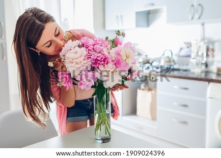 Valentine's day. Woman smelling bouquet of peonies at home. Housewife received present for holiday. Allergy free Royalty-Free Stock Photo #1909024396