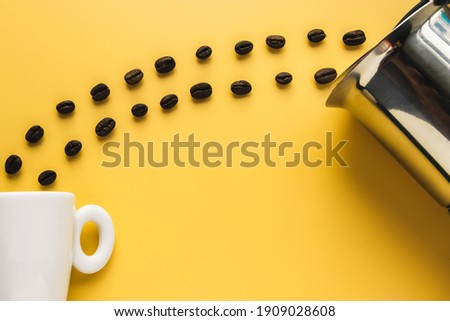Top view image of a cup and coffee beans on yellow background. Copy space