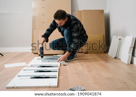 Portrait of man assembling furniture. Do it yourself furniture assembly. Royalty-Free Stock Photo #1909041874
