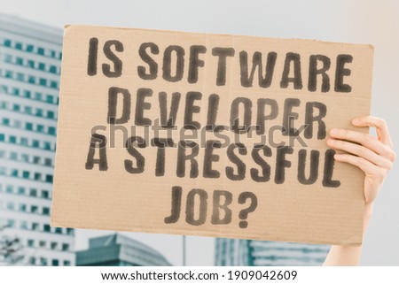 The question " Is software developer a stressful job? " on a banner in men's hand with blurred background. Profession. Problem. Hard. Occupation. Work. Brain. Healthcare. Stress. Trouble. Programming