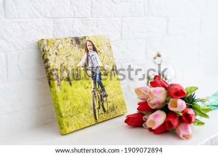 photo canvases of active little girl and flowers tulips as a holiday gift lie on the shelf