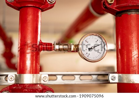 Red pipes and pressure gauge of a hydraulic installation for fire fighting