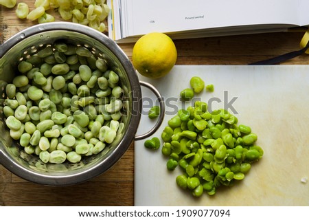 Cooking broad beans for a meal. Lemons and broad beans with chopping board. Preparing beans for dinner. Ottolenghi recipe.  Royalty-Free Stock Photo #1909077094