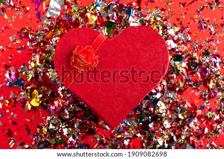 Present or gift box heart shaped and confetti on red background, copy space