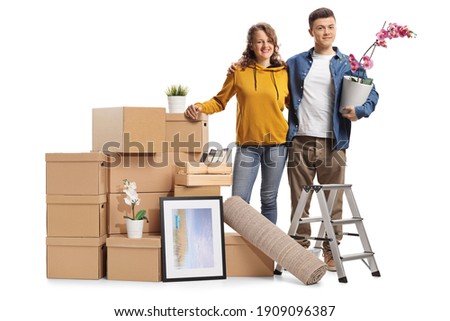 Young male and female posing with a pile of packed cardboard boxes isolated on white background