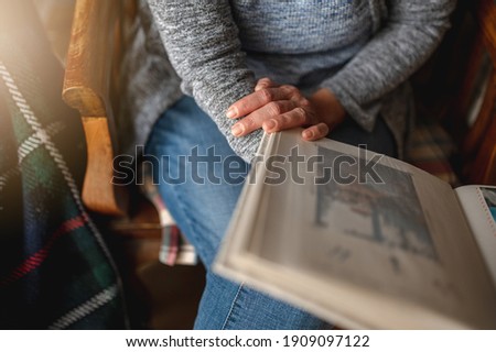 Close-up unrecognizable woman holding a photo album sitting on the sofa. Memories concept.
