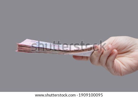 Hand holds a stack of 200 hryvnia bills, side view. High quality photo