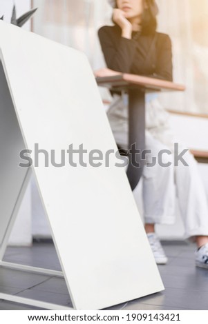 Vertical white signage front store with a blurred woman, Perspective view.