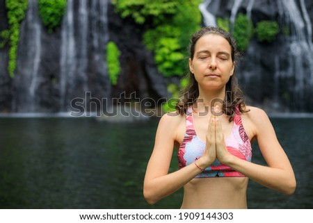 Namaste mudra. Close up. Yoga near waterfall. Young woman meditating, practicing yoga and pranayama with namaste mudra. Yoga outdoor concept. Copy space. Retreat in Bali. Banyumala waterfall.
