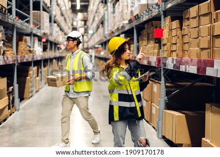 Asian two engineer in helmets team order details on tablet computer for checking goods and supplies on shelves with goods background in warehouse.logistic and business export Royalty-Free Stock Photo #1909170178