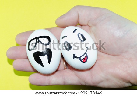Chicken eggs with painted faces on the hand.