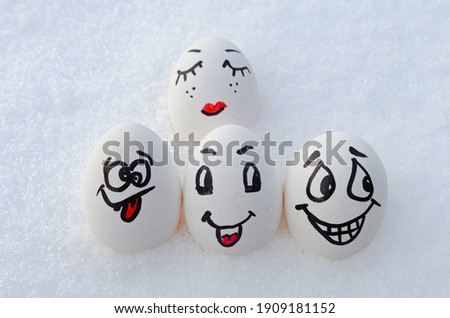 Chicken eggs with painted faces in the snow.