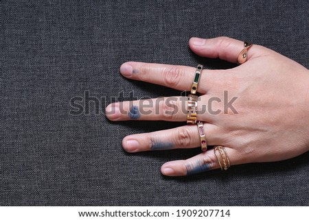 Rings on each finger with blue inked fingers