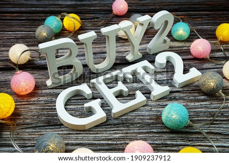 Buy 2 Get 2 Word alphabet letters on wooden background