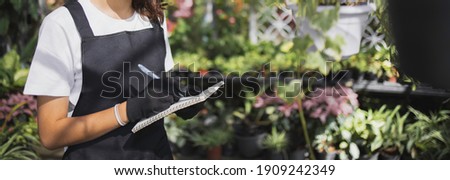 Small business entrepreneur concept, Female gardener hand writing notebook working on gardening growing tree at greenhouse