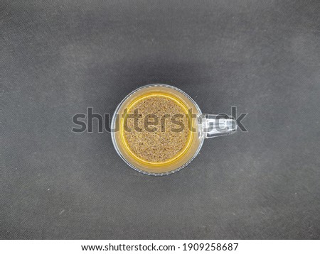 boiling hot and freshly made indonesian style coffee or kopi tubruk in a glass mug. picture taken from above with black background