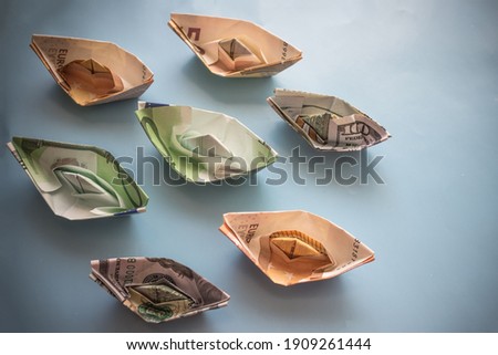 Cancellation of cruise flights, losses of shipping companies. Ships made of notes, euros and dollars. Copy space. Top view, vignetting.