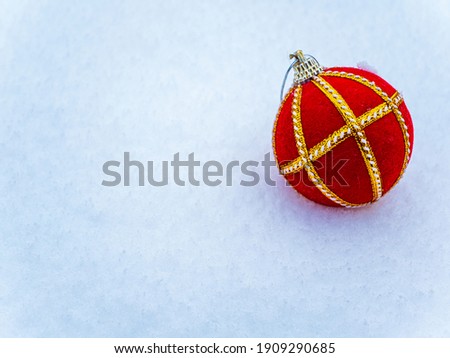 Red ball Christmas tree toy with gold edging on the snow. Merry Christmas. Festive spruce decor. Happy New Year. Red sphere. White snow. Background image. Greeting card. Frosty weather.