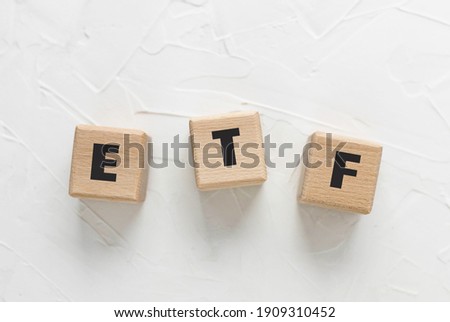 Text ETF on wooden cubes on white textured putty background.    Abbreviation of 'Exchange Traded Funds'. Square wood blocks. Top view, flat lay.