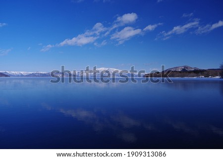 A scenic view of the snowy mountains from a still water lake.