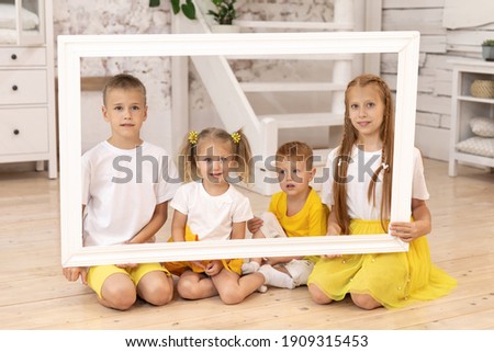 Smiling children holding picture frame. four children. brothers and sisters