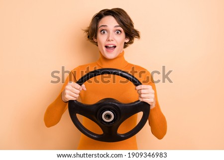 Photo of funny impressed young girl orange turtleneck holding steering wheel isolated beige color background Royalty-Free Stock Photo #1909346983