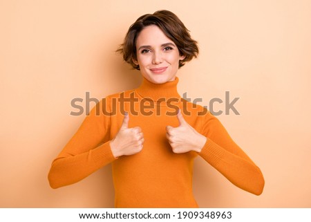 Photo of funny sweet young girl orange turtleneck showing thumbs up two hands arms isolated beige color background
