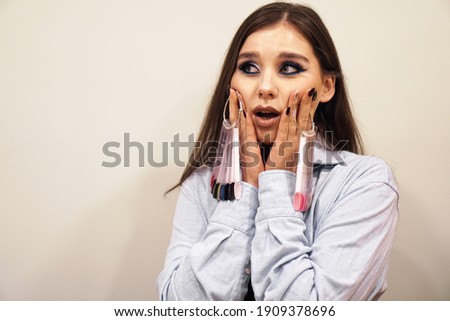 Woman holding a palette of nails. She is impressed. Comic concept - the choice of nail color for girls in a beauty salon.