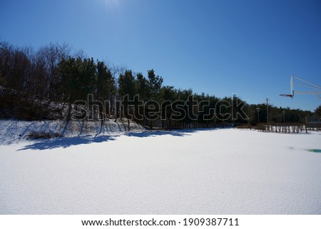 Outdoor basketball court covered with snow