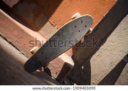 A skateboard rests against a wall exposed to sunlight