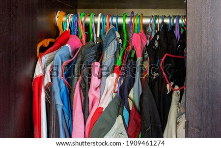 Men's and women's clothes on hangers in a messy closet
