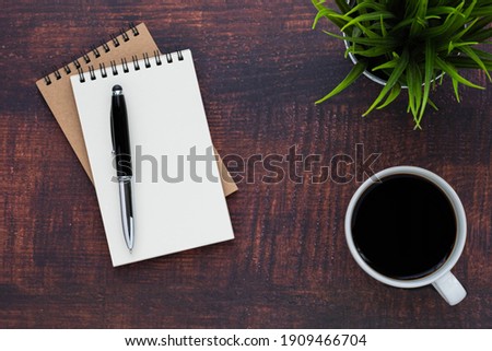 Top view of open school notebook with blank pages, coffee cup and pen for taking write notes on wood table background. Flat lay, creative workspace office. Business-education concept with copy space.
