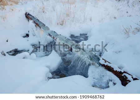 Break of a communal water pipe in the winter. Pure water flows from a rusty pipe. There is snow all around. High quality photo