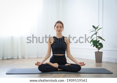 Young woman practicing lotus asana in yoga studio. Padmasana pose Royalty-Free Stock Photo #1909519561