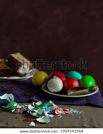 Still life with slices of Easter cake and colored eggs on rustic background. Vertical image with copy space
