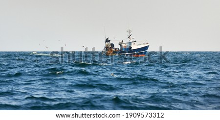 Small fishing boat sailing in an open Mediterranean sea, close-up. A view from the yacht. Leisure activity, sport and recreation, food industry, traditional craft, environmental damage concepts Royalty-Free Stock Photo #1909573312