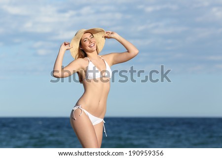 Happy fitness woman body posing on the beach with the horizon in the background     