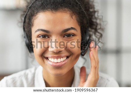 Headshot portrait close-up smiling African American woman support service operator in headset wireless headphones with microphone, smiling, working and looking at the camera, satisfied worker concept Royalty-Free Stock Photo #1909596367
